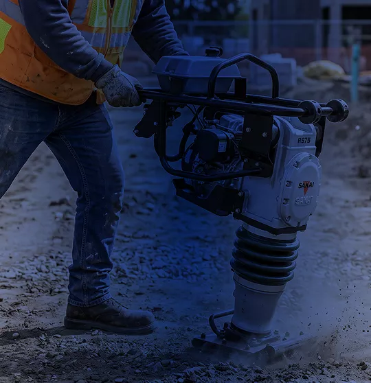 Operario utilizando bailarina compactadora Sakai para compactación de tierra en zanja