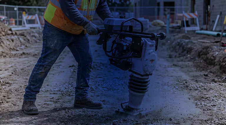 Operario utilizando bailarina compactadora Sakai para compactación de tierra en zanja